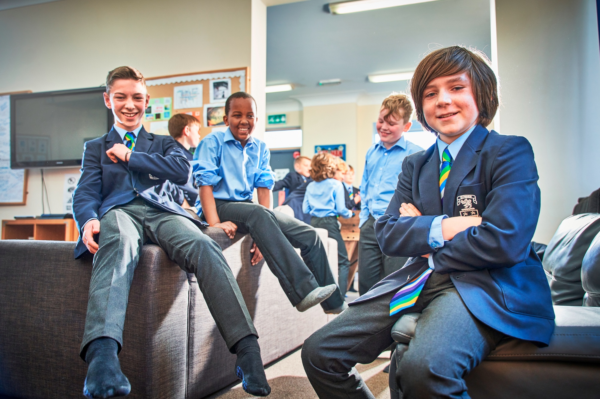 several year 7 boys sitting on the backs of sofas posing for the camera in the boarding house