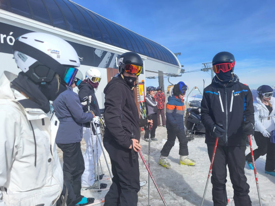 Students will full ski gear, helmets and goggles at the top of a snow mountain