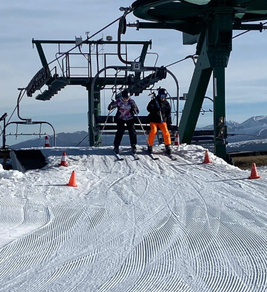 Two students attempting to get off a ski lift 