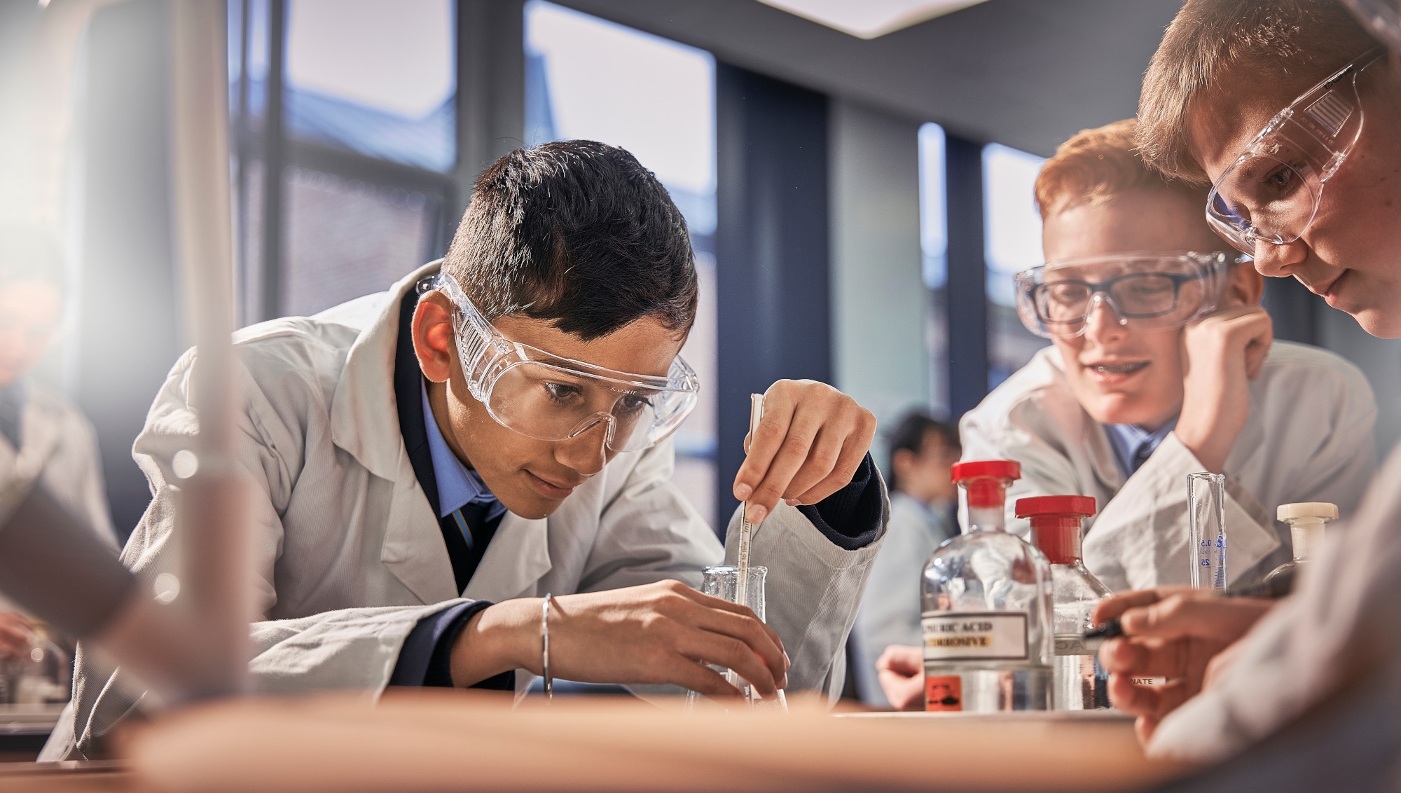Two students in lab coats conducting a science experiment with beakers and chemicals