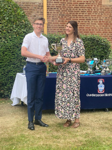 Sixth Form male student wearing shirt and trousers collects a trophy from Cat Eccles MP, shaking hands and smiling at the camera