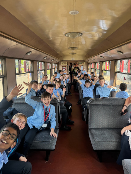 Students smiling and waving aboard a rail carriage
