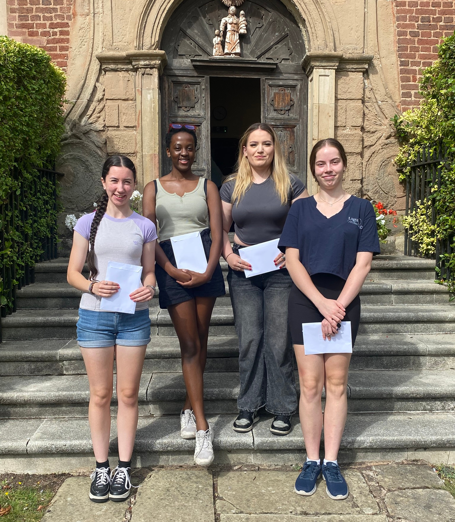 smiling students pose with their results envelopes