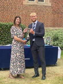 Sixth Form male student wearing collects an trophy from Cat Eccles MP, shaking hands and smiling at the camera