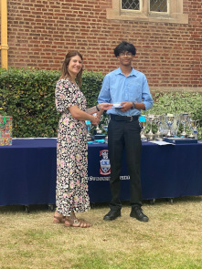 Junior male student wearing OSH uniform collects an award from Cat Eccles MP, shaking hands and smiling at the camera