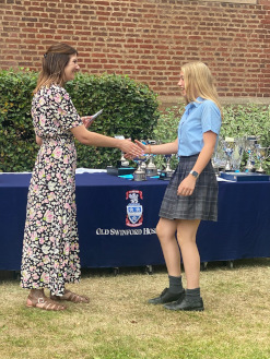 girl in OSH school uniform collecting award, shaking hands with Cat Eccles MP