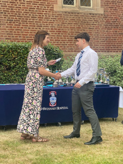 Male Sixth Form student wearing a suit collects his award, shaking hands with Cat Eccles MP