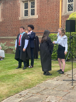 Outgoining Heads of School students presenting medals to incoming Heads of Schools, shaking hands and smiling
