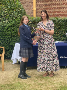 Junior female student in OSH uniform collects an award, shaking hands with Cat Eccles MP and smiling at the camera