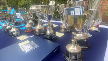 Silver trophies displayed on a blue table-top