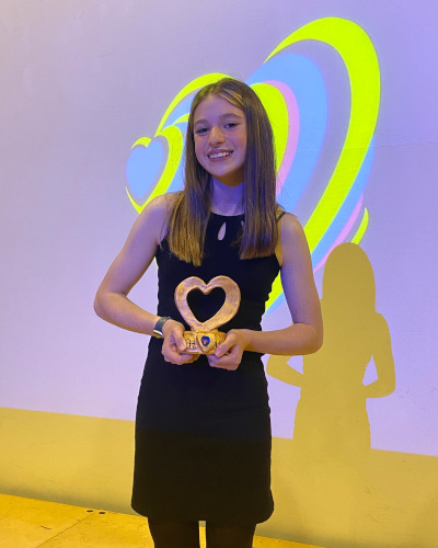 Winner of the inaugural OSHVision, Poppy stands beaming holding her heart-shaped trophy