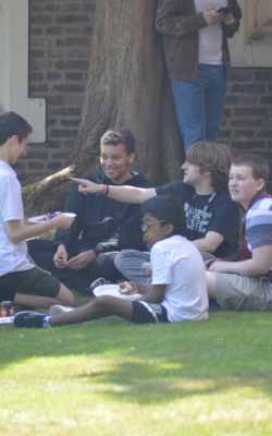 5 boys sit on the grass enjoying a bbq