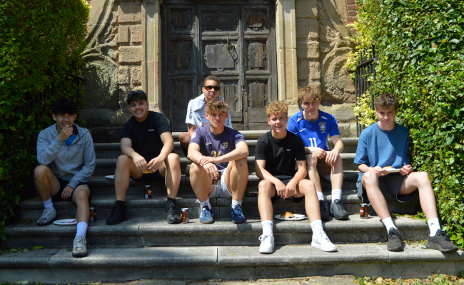 7 boys in sportwear sit casually on steps in the sunshine