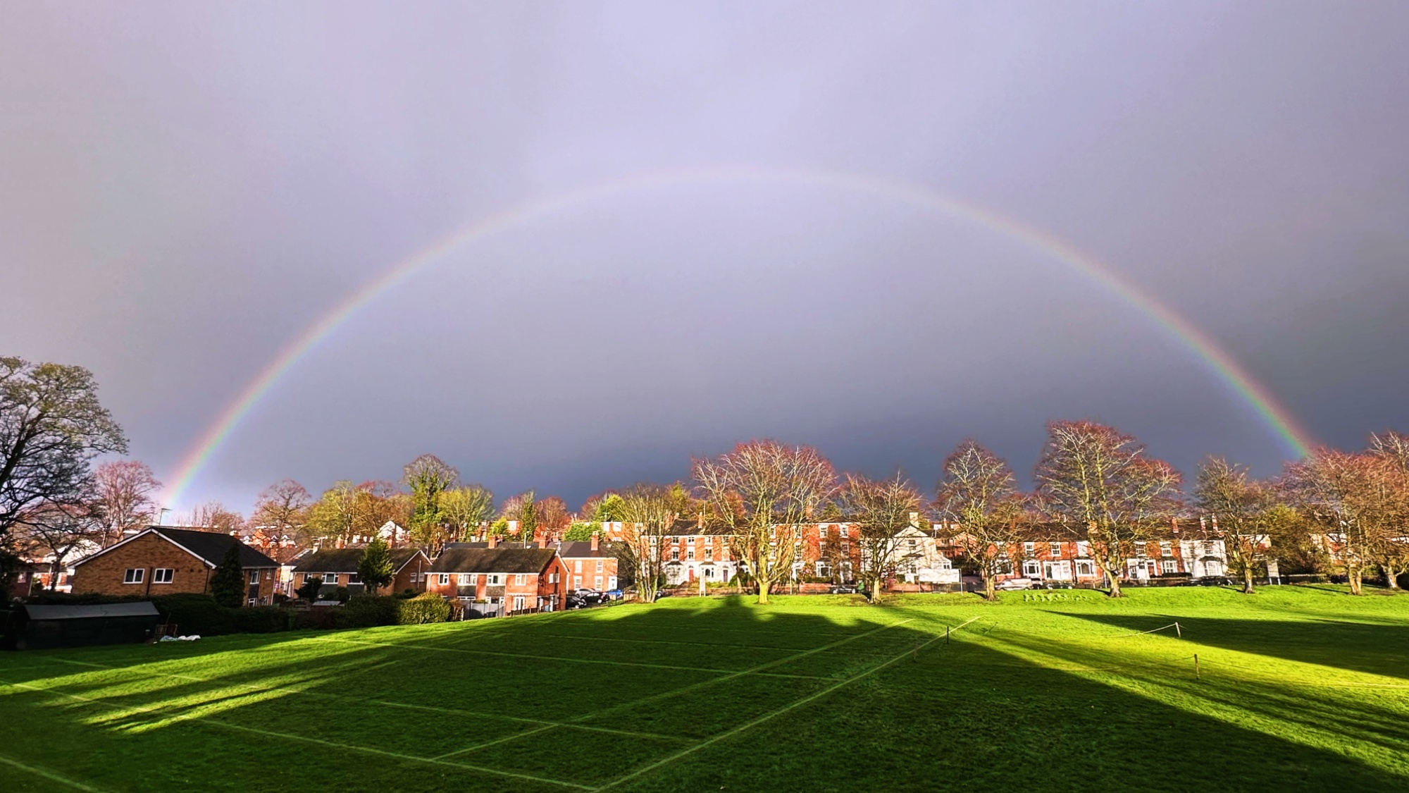 Full rainbow over a green cricket field
