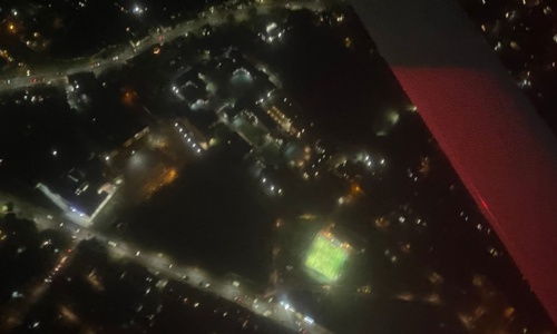 Arial photo of OSH site at night lit up with street lights, clearly showing boarding houses and sports pitches